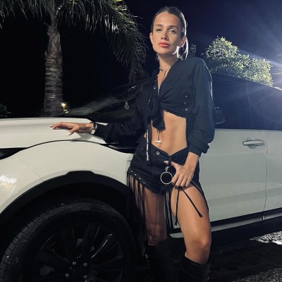 Cami Homs posed infront of a white car.